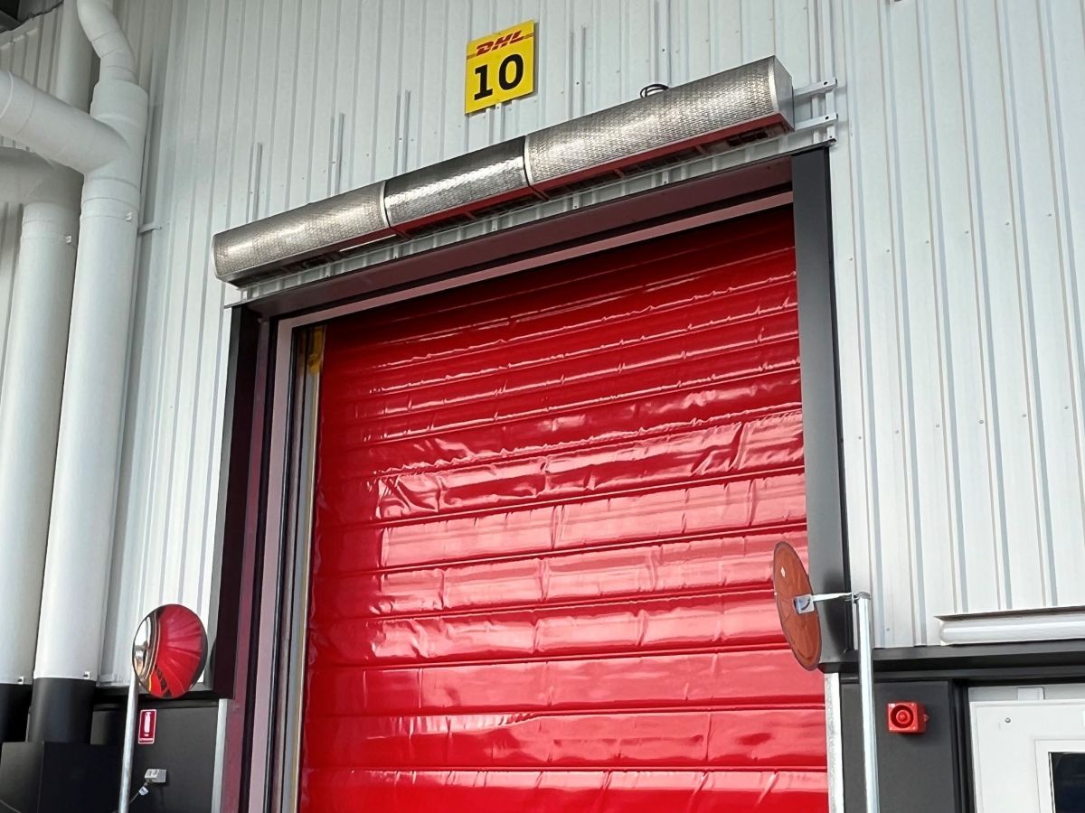 An industrial air curtain above a high speed door on the outside of a warehouse.