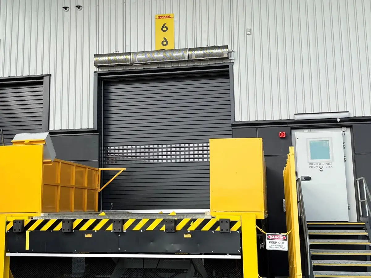 An Industrial air curtain above a customised roller shutter on the exterior door of an industrial warehouse facility of DHL Brisbane Airport