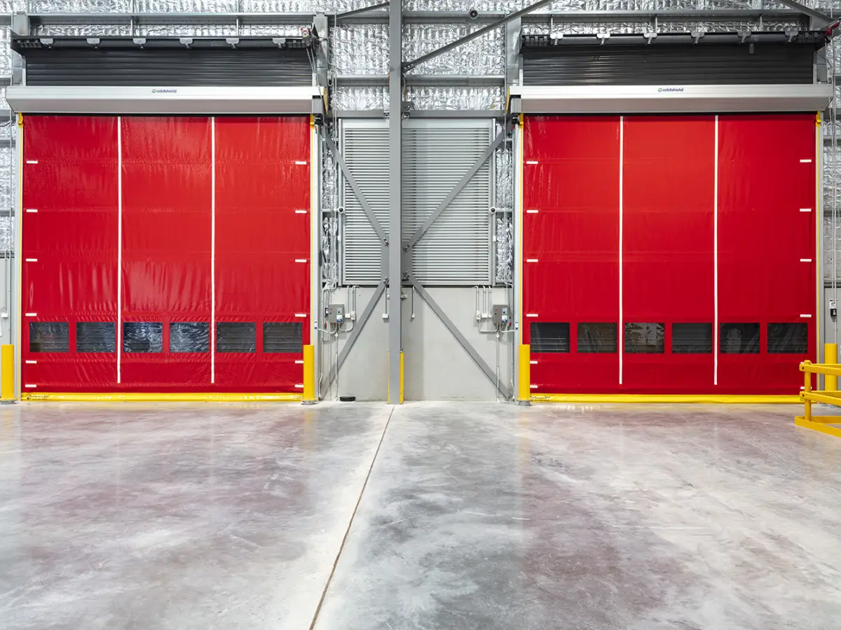 Two red HS series doors closed inside a factory with large doorways