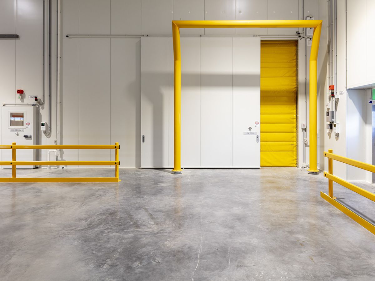 A closed thermal high speed door with a partially closed sliding door across it inside a factory of DHL Brisbane Airport