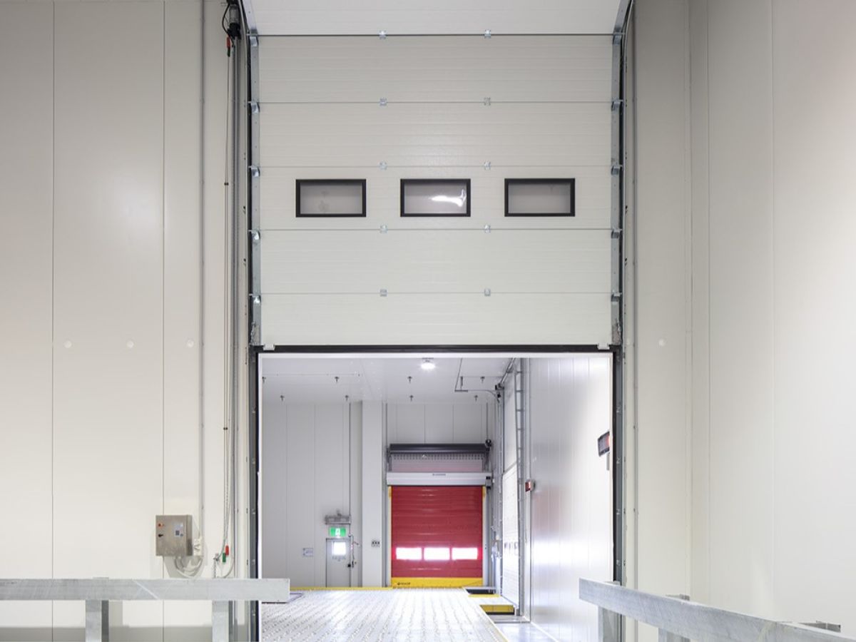 A partially open sectional door through which a high speed door can be seen.