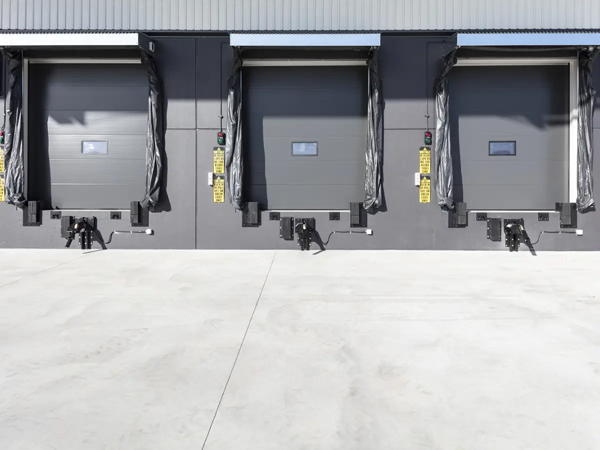 Three large closed sectional doors on a loading dock on the outside of a warehouse at DHL Brisbane Airport