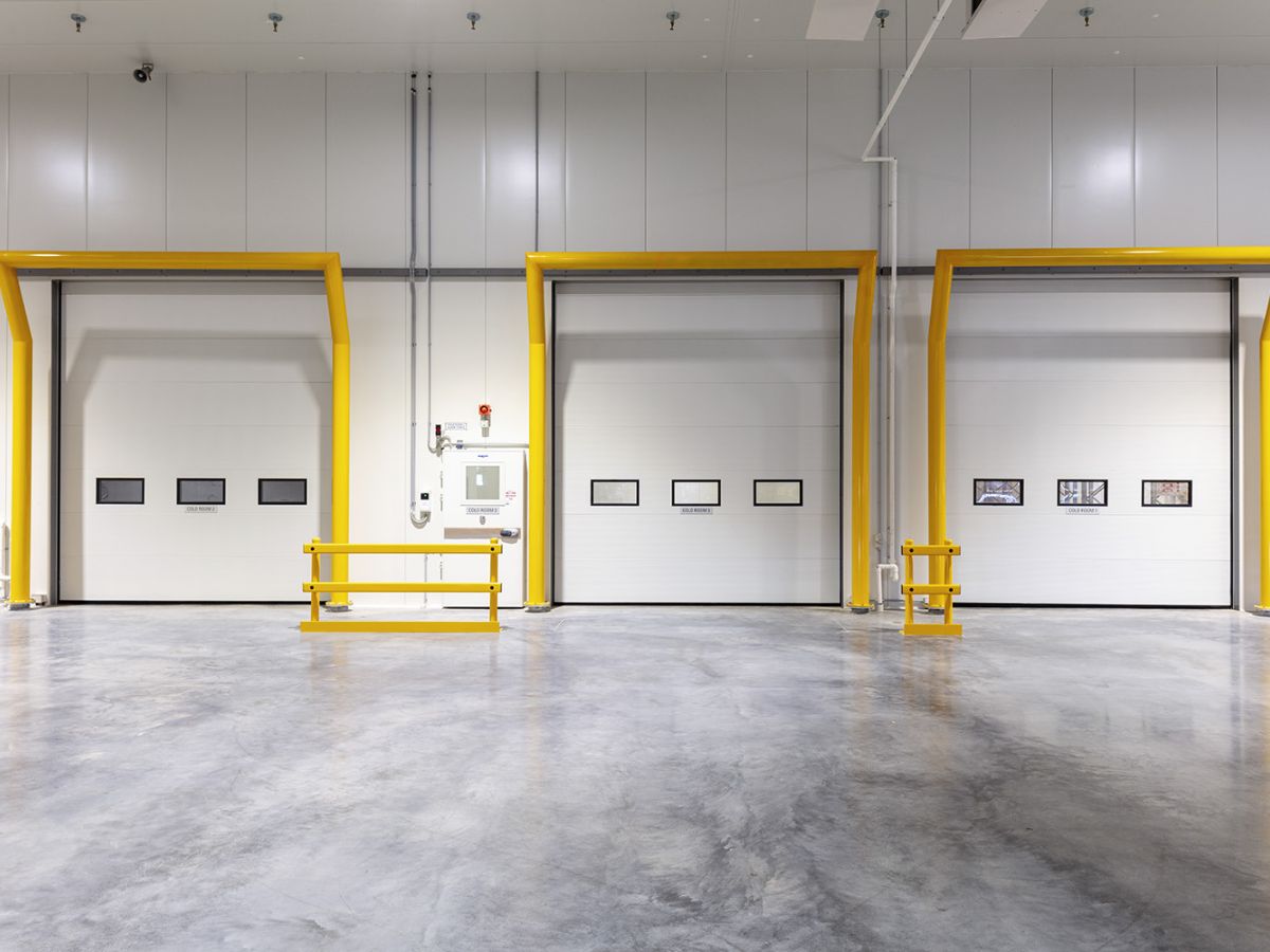 Three large sectional doors on the inside of an empty warehouse.