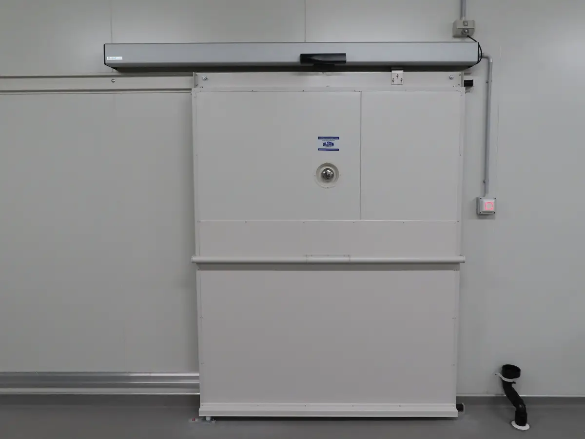 A automatic sliding door to a cold room of Tasty Fresh; with an automatic sensor operator on top.