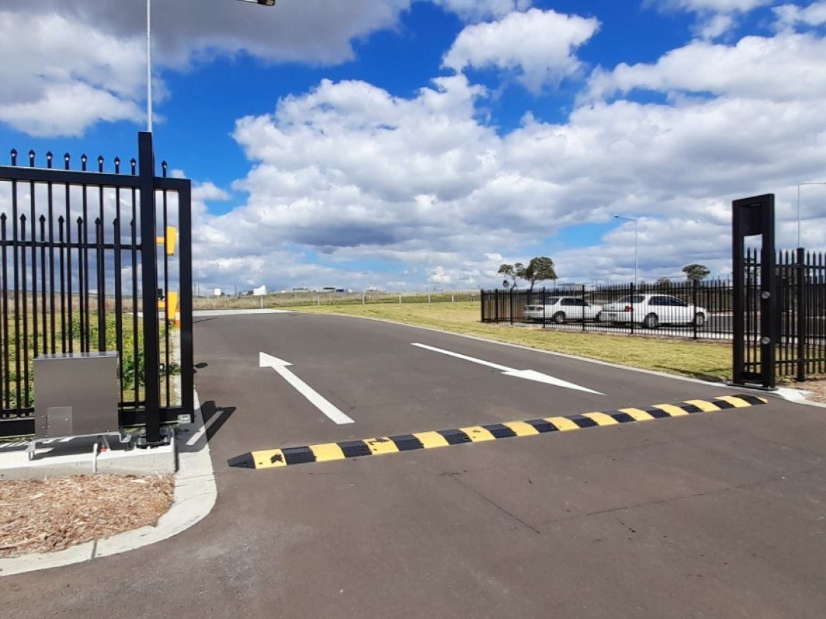 Cantilever automatic gate shown open at an industrial park of Toowoomba Regional Council; AUTOMATIC GATE CONTAINS magnetic ground loops for vehicle protection.