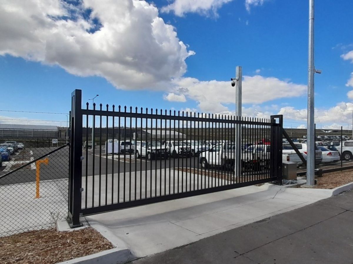 A closed industrial gate leading to car park; custom automatic gate shown with cantilever