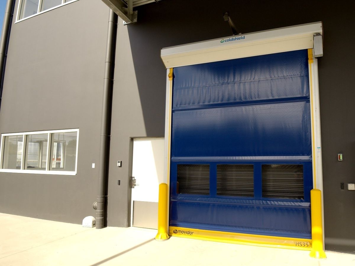 A closed high speed door on the outside of a factory.