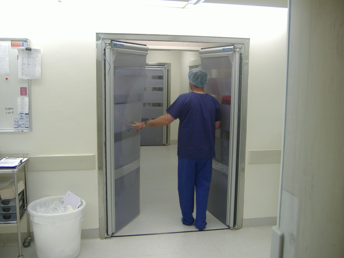 A hospital worker opening a PVC swing door in a hospital.