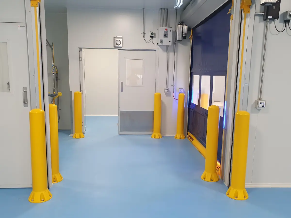Several yellow bollards shown inside a factory protecting wall and entrances including a movidor high speed rapid roller door.