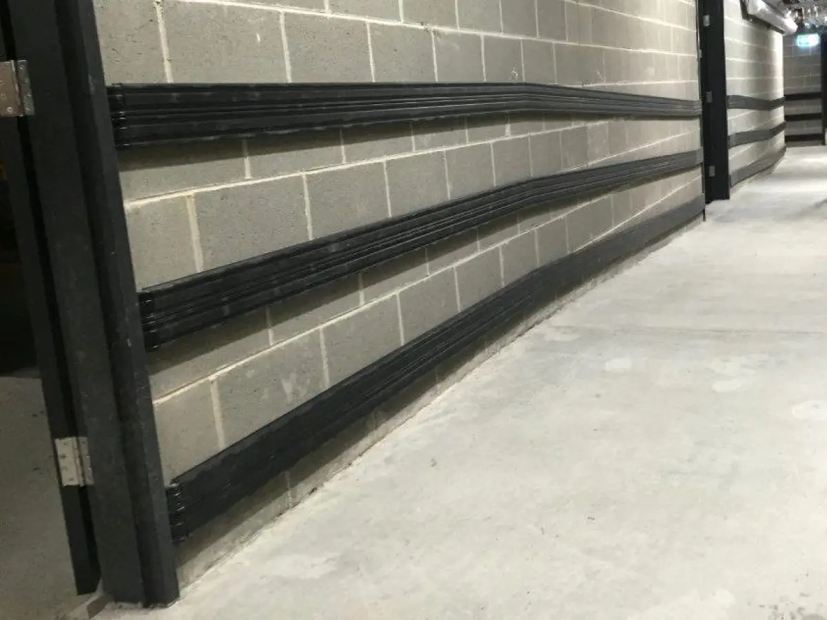 Black PVC bum prails along a corridor wall inside a building; bump rail wall protection system is ultra-durable and can withstand heavy impact