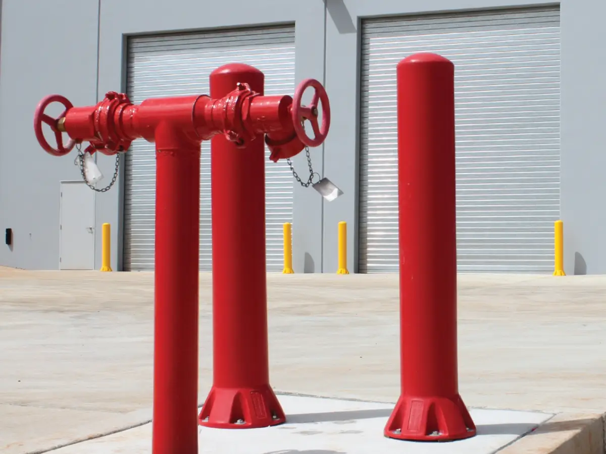 Highly visible bollard set; red polyethylene bollards outside an industrial factory for door and wall protection.