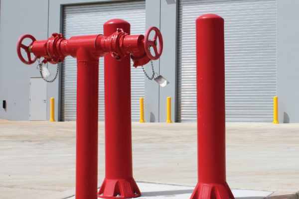 Highly visible bollard set; red polyethylene bollards outside an industrial factory for door and wall protection.