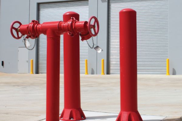 Red polyethylene bollards outside an industrial factory.