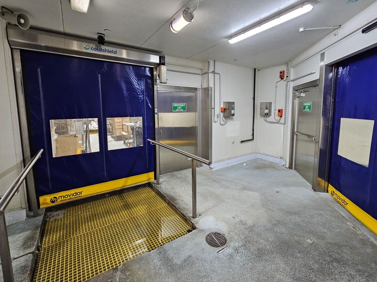 Two closed blue high speed doors inside a factory.