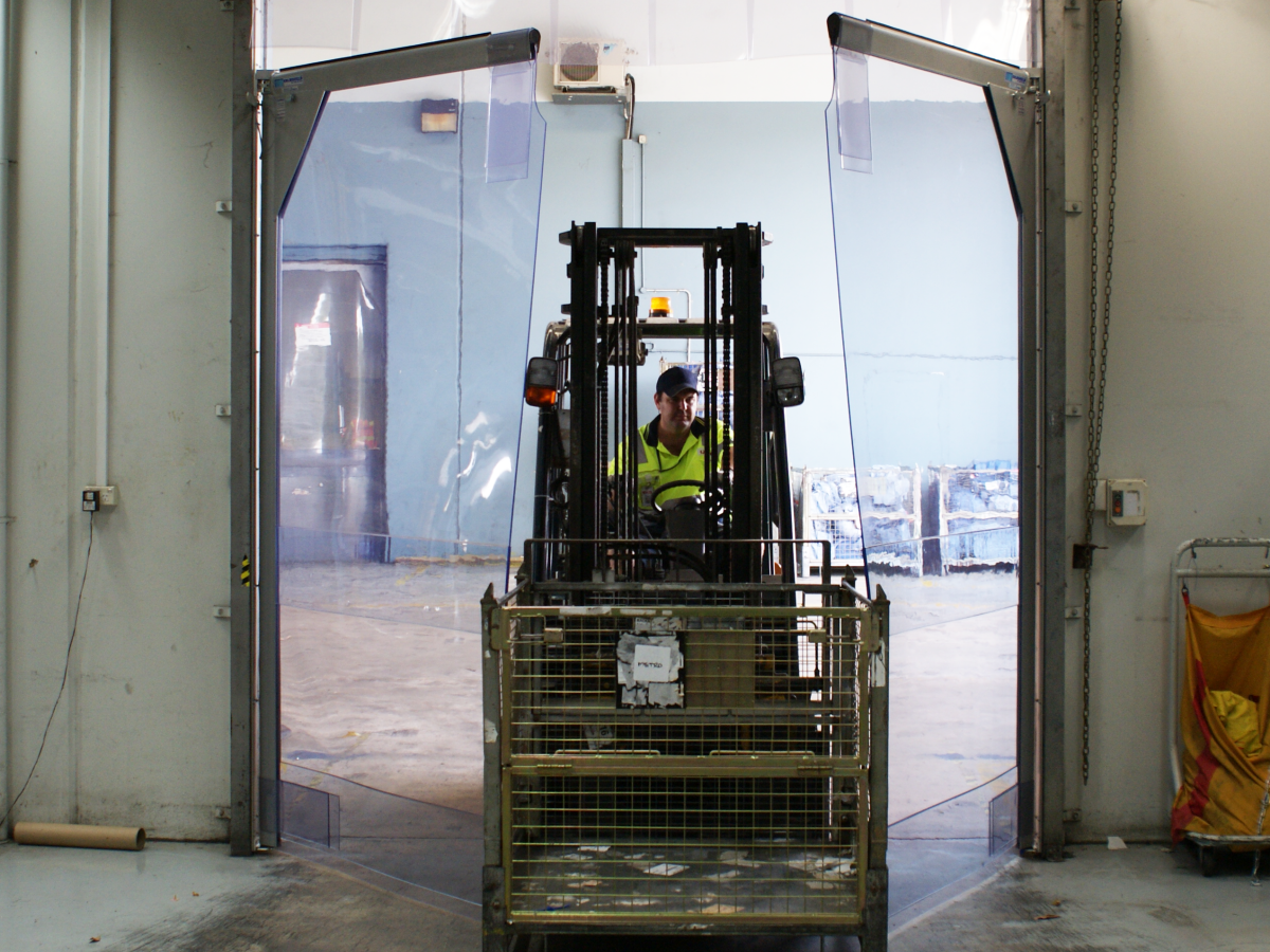 A forklift driving through 3000 Series PVC swing doors in Australia Post Brisbane Airport