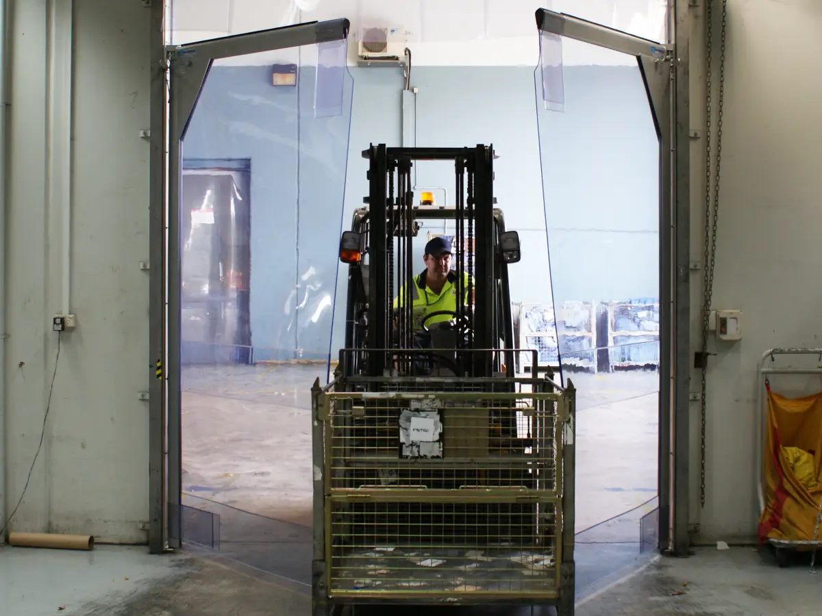 A forklift driving through 3000 Series PVC swing doors in Australia Post Brisbane Airport