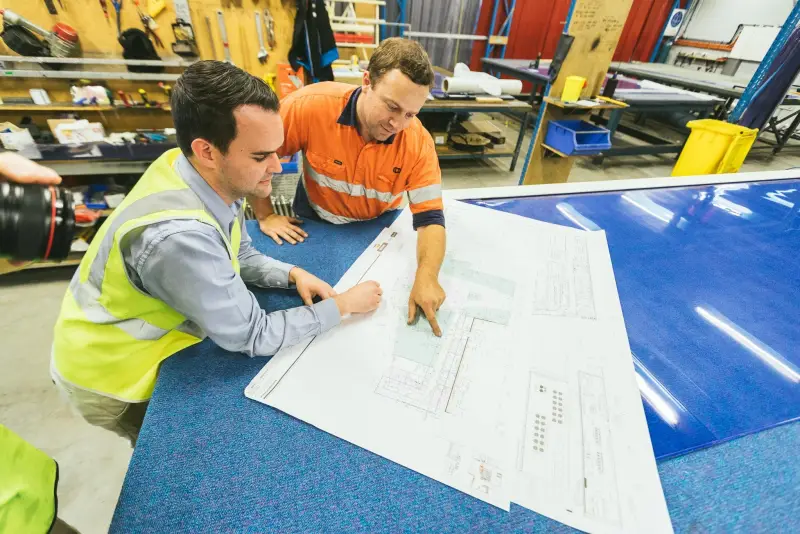 Two Australian Coldshield employees looking at a custom doorway plan including high speed doors, swing doors, and strip curtains