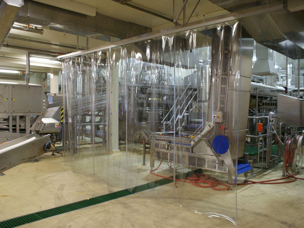 A clear plastic, PVC strip screen; industrial strip curtain used to protect factory equipment in commercial manufacturing facility