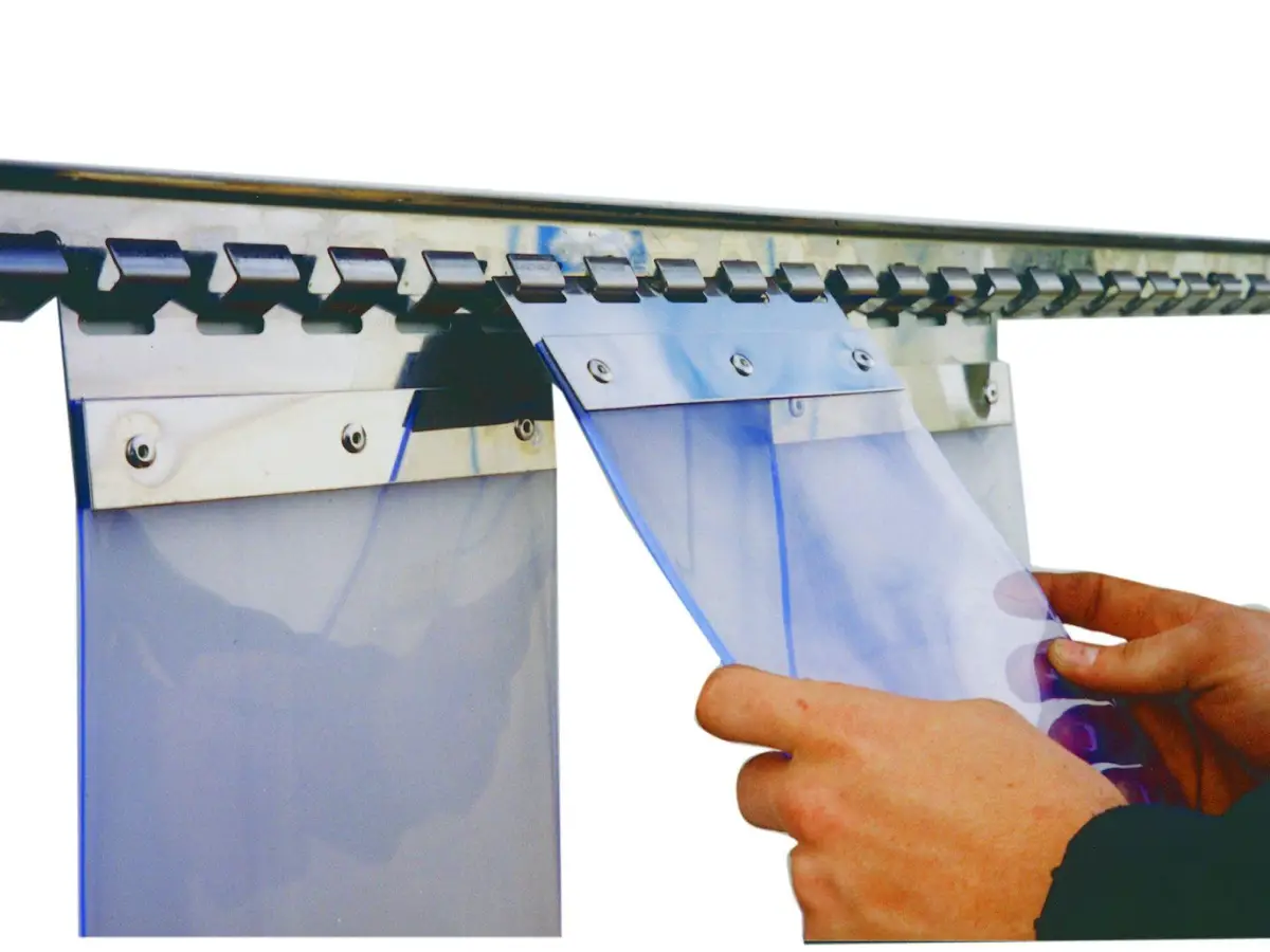 A PVC strip curtain mounting system; clear plastic strips with a hook being attached to a cool room traffic door on mounting system.
