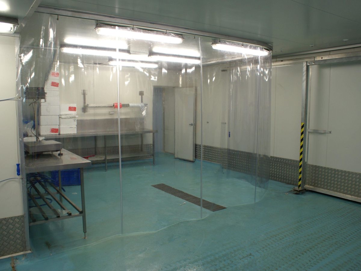 A highly durable, flexible PVC screen curtain, acting as a barrier separating a work area in a commercial food processing factory of Super Fin