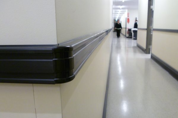 Black plastic PVC  bumprails protecting walls inside a healthcare facility.
