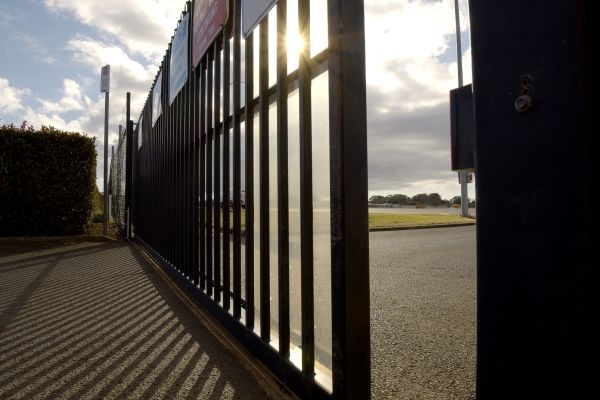 A black metal automatic commercial gate starting to open.