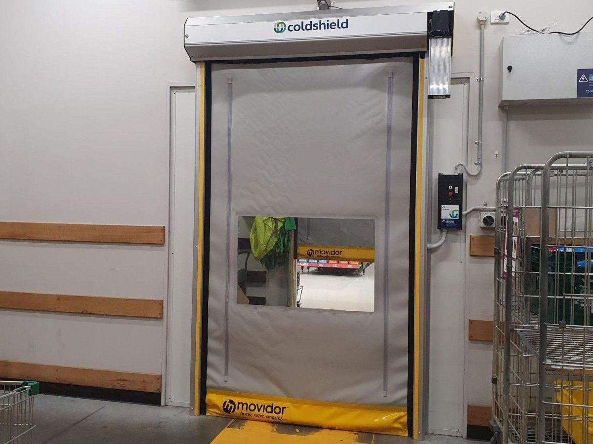 A grey high speed rapid door viewed from the staff area of a supermarket.