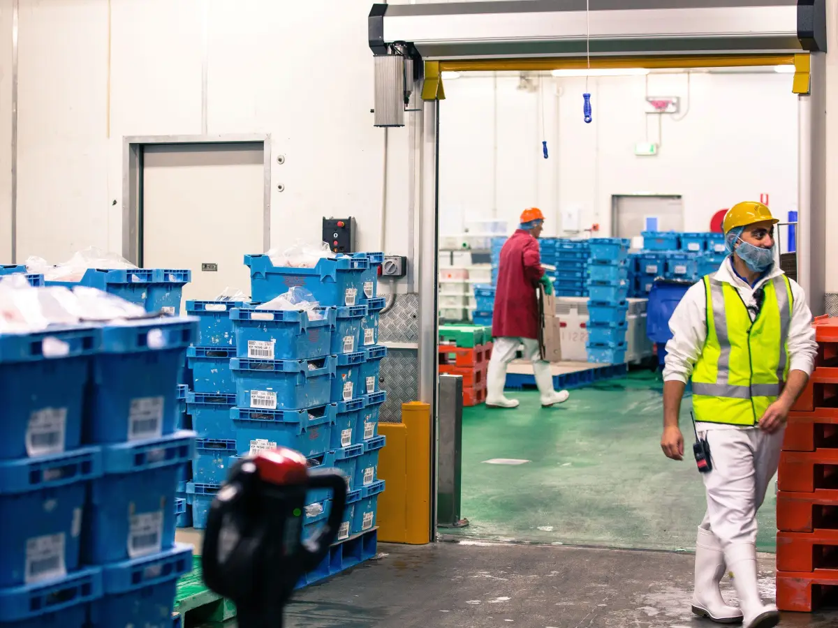 A man walking through an open high speed door at a food processing factory.