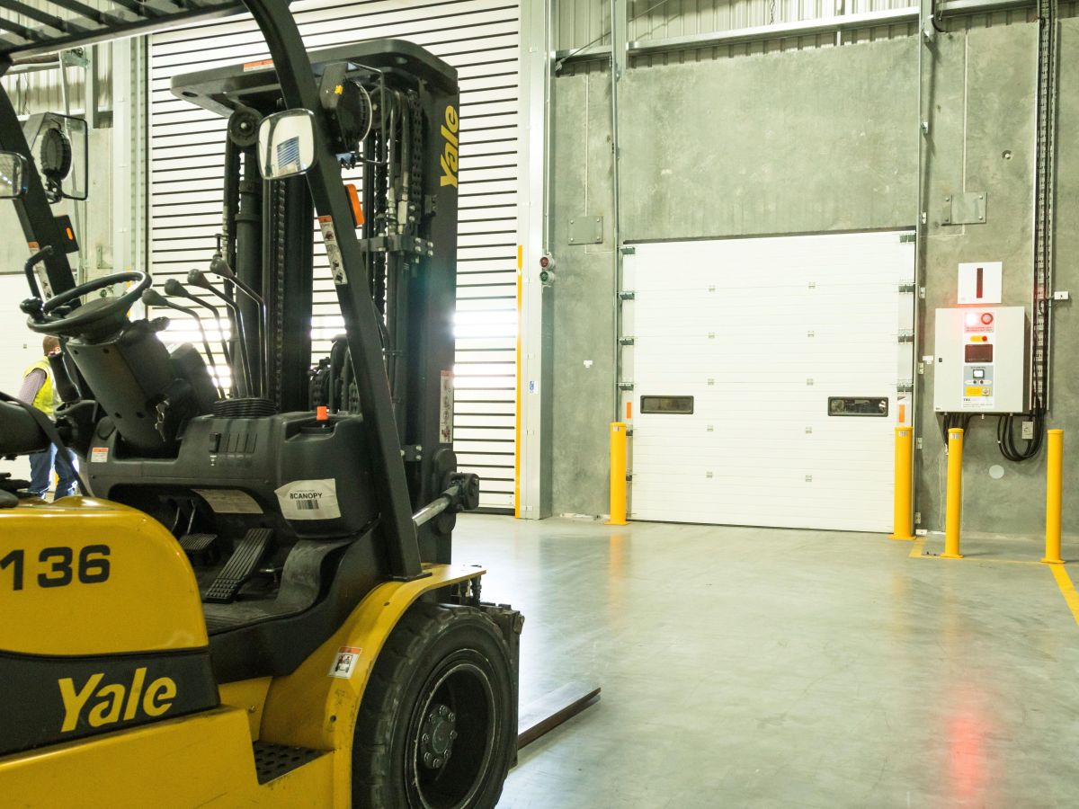 A sectional door and a forklift inside a factory.