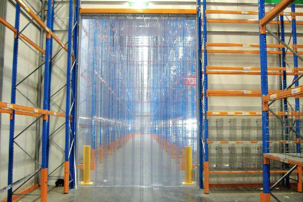 PVC plastic sheet strip curtains on an insulated fridge door frame within a food production & manufacturing warehouse of Subzero